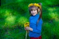 Little girl on a green grass in a wreath of flowers in spring Royalty Free Stock Photo