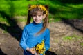 Little girl on a green grass in a wreath of flowers in spring Royalty Free Stock Photo