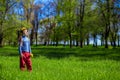 Little girl on a green grass in a wreath of flowers in spring Royalty Free Stock Photo