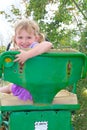 Smiling little toddler girl on a green tractor seat