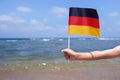 Little girl hands hold Germany flag against the sea horizon. 3th of October Independence day of Germany, concept.