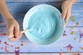 A little girl hands making slime herself on blue wooden background