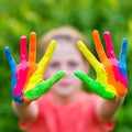 Little girl with hands painted in colorful paints ready for hand prints