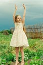 A little girl with hands raised up in nature shows freedom. Teenage girl in a floral dress in summer