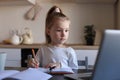 Little girl handwrite study online using laptop at home, cute happy small child take Internet web lesson or class on PC