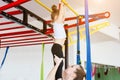 Little girl hanging on the crossbar, mom supports