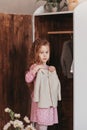 Little girl hangs clothes in a closet