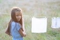 Little girl hangs out to dry retro doll clothes, summer nature outdoor. Washing, children`s games, kid`s leisure