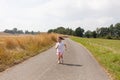 Little girl happily running along a quiet rural road, surrounded by the beauty and tranquility of the countryside Royalty Free Stock Photo