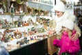 Little girl with happy mom buying figures and workpiece for creating Christmas scenes