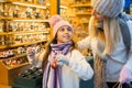 Little girl with mom buying figures and workpiece for creating Christmas scenes