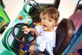 Little girl is happy sitting on the driver`s seat of the children`s car Royalty Free Stock Photo