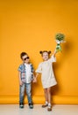 Young happy caucasian boy gives a flowers to his girlfriend isolated over yellow background. Royalty Free Stock Photo