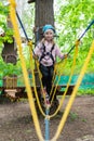 Little girl in harness crossing rope bridge in a ropes course Royalty Free Stock Photo