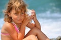 Little girl has leant seashell bowl to an ear