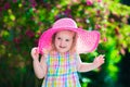 Little girl in a hat in blooming summer garden