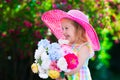 Little girl in a hat in blooming summer garden Royalty Free Stock Photo