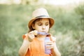 A little girl in a hat blowing soap bubbles in summer day Royalty Free Stock Photo