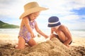 Little Girl in Hat Boy Spread on Sand Heap on Beach by Surf