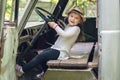 Little girl in a hat sits behind the wheel of an old disassembled car Royalty Free Stock Photo