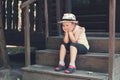 Little girl in a hat sits and dreams on the porch of an old wooden house Royalty Free Stock Photo