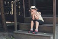 Little girl in a hat sits on the porch of an old wooden house Royalty Free Stock Photo