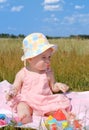 Little girl in a hat sitting on green field Royalty Free Stock Photo