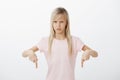 Little girl hates washing dishes. Portrait of displeased disgusted cute young daughter with blond hair, pointing down