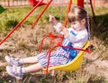 A little girl is having fun on a chain carousel. A cute little girl is riding on a swing. A beautiful little girl is riding on a r