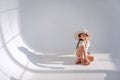 Little girl is having fun on the floor in stylish hat in a white loft interior with airy fabrics Royalty Free Stock Photo