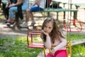 Little girl having fun on a swing outdoor. Sad girl sitting alone on a swing in a park playground. Charming stylish Royalty Free Stock Photo