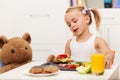 Little girl having a healthy snack sitting at the table with her Royalty Free Stock Photo