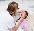 Little girl having his throat examined by health professional