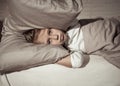 Little girl having trouble sleeping at night holding pillow covering her head and ears upset Royalty Free Stock Photo