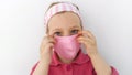 Little girl in headband and protective pink mask against coronavirus COVID-19 pandemic white background on quarantine Royalty Free Stock Photo