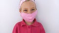 Little girl in headband and protective pink mask against coronavirus COVID-19 pandemic white background on quarantine Royalty Free Stock Photo