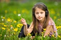 Little girl in headphones sitting in the green grass. Happy. Royalty Free Stock Photo