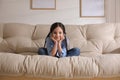 Little girl with headphones sitting on sofa at home Royalty Free Stock Photo