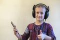 Little Girl Headphones Using Phone. thumbs up Royalty Free Stock Photo