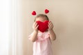 Little girl with heart shaped pillow indoor, hiding behind heart. Concept of love, happiness, kindness, gift, handmade Royalty Free Stock Photo