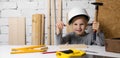 Little girl with helmet learn to hammer a nail in wooden plank at woodworking workshop. copy space Royalty Free Stock Photo