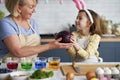 Little girl helping grandmother prepare natural dyes for coloring eggs