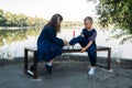 Little girl helps boy brother tie shoelace on bench in park. sister tying laces on shoes brother. Girl friend teaches Royalty Free Stock Photo