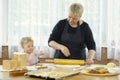 A little girl helps her grandmother roll out the pizza dough. Royalty Free Stock Photo