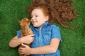 Little girl with her Chihuahua dog lying on grass, top view. Childhood pet Royalty Free Stock Photo