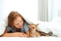 Little girl with her Chihuahua dog under blanket at home. Childhood pet Royalty Free Stock Photo