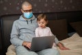 Little girl and her father in mask with laptop at home