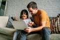 Little girl and her father using a laptop together at home. Royalty Free Stock Photo