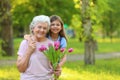 Little girl with her grandmother and  of flowers in park. Space for text Royalty Free Stock Photo