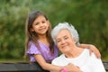 Little girl and her grandmother hugging on bench